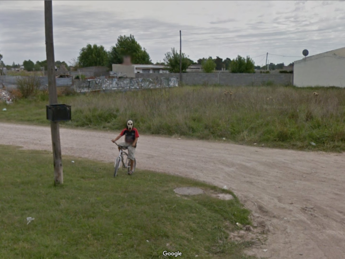 A young boy rides a bike wearing a terrifying "Scream"-inspired mask in Azul, Buenos Aires. This is not a place where I would want to walk alone at night.