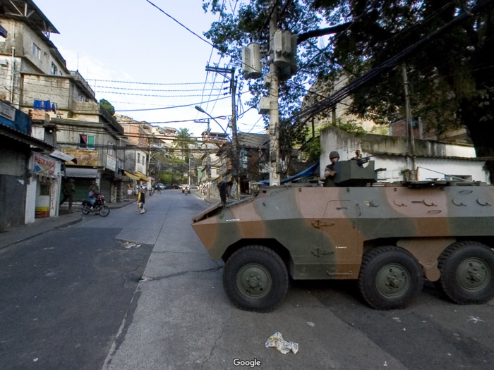 A tank casually rolls down the streets of Rocinha near Rio de Janeiro, Brazil, as people walk by.