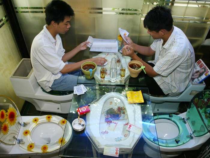 Customers play cards on toilet seats at a commode-themed restaurant in Shenzhen, in south China