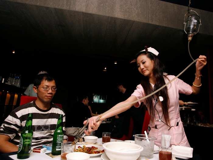 At a hospital-themed restaurant in Taipei, a waitress dressed in a nurse uniform serves a drink to a customers using a drip.