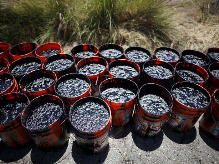 Volunteers carried buckets of oil from an oil slick along the coast of Refugio State Beach in Goleta, California on May 20, 2015.