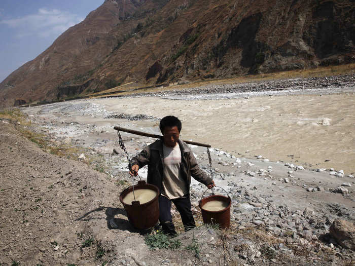 A villager carries buckets of his daily drinking water from a white, polluted stream in Dongchuan district of Kunming, Yunnan province on March 20, 2013.