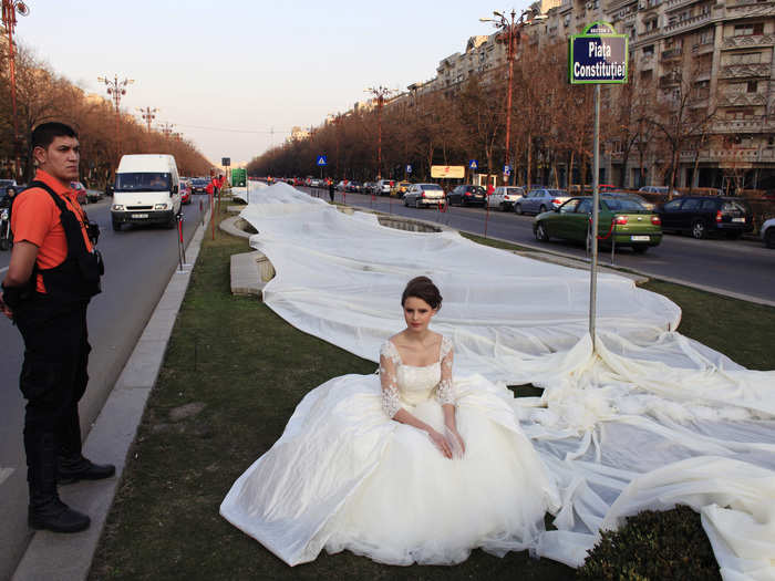A Romanian woman wears a wedding dress with the longest train in the world during a Guinness World Record attempt in Bucharest.