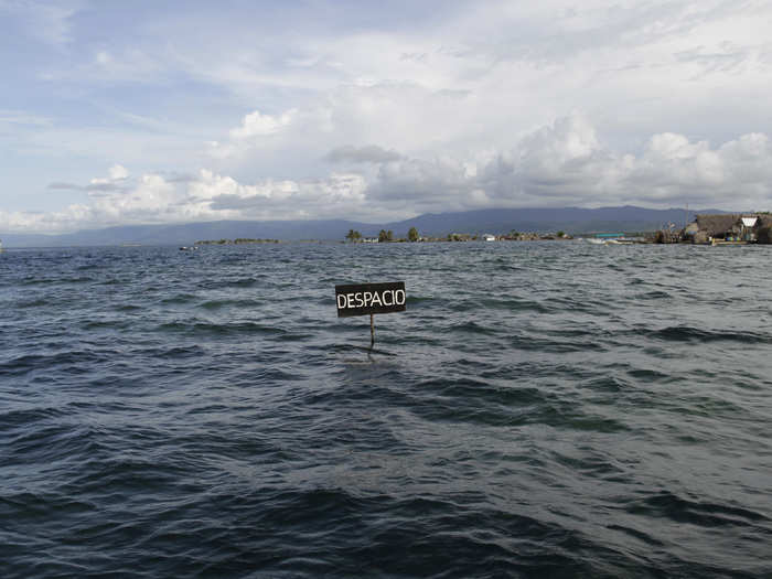 SAN BLAS ARCHIPELAGO NOW: The Caribbean island communities are flooded for several days every rainy season as a result of rising ocean levels caused by global warming. In the foreground, a traffic sign reading "Slow Down" is partially submerged.