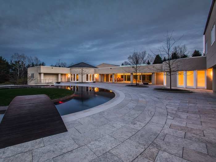 The backyard has a reflecting pool with a lawn in the center. A bridge can take you across and back.