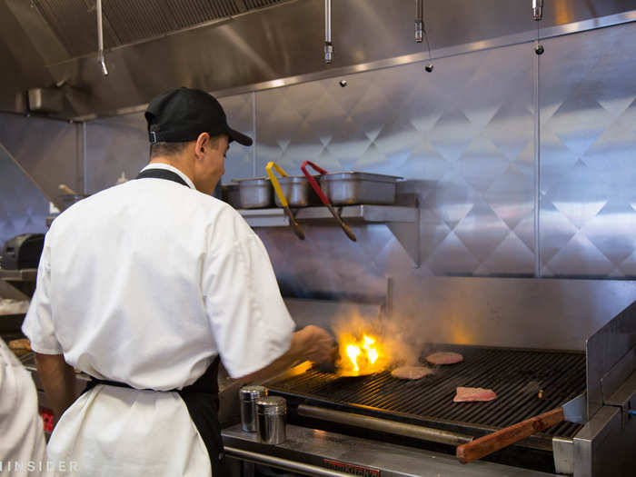 A kitchen manager tossed two patties over an open flame grill, which is hard to come by in the fast-food industry.