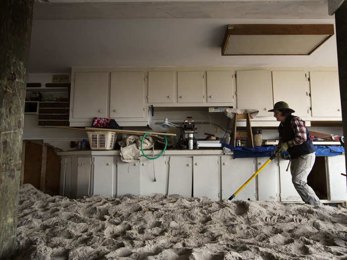 Over in the New Jersey town of Mantoloking, a woman works to remove sand from her parents