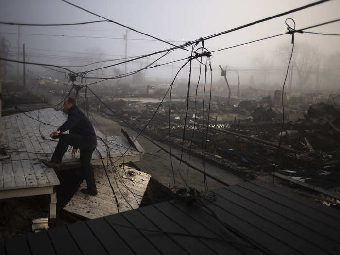 An insurance claims adjuster scales the entrance to a house in Breezy Point.