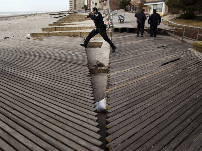 Over in Belle Harbor, Brooklyn, an NYPD officer jumps over a split in the boardwalk.