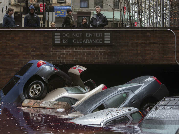 Down in Lower Manhattan, residents stand over vehicles that have been submerged in a parking structure.