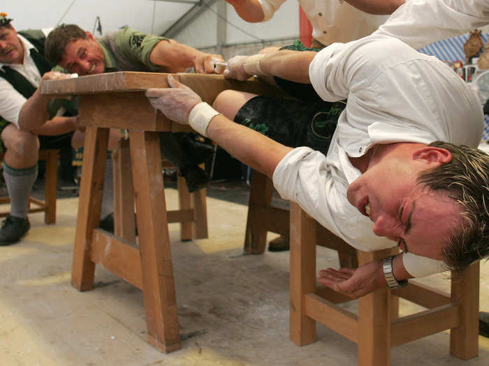 Bavarian men try to pull one another across the table as part of the country