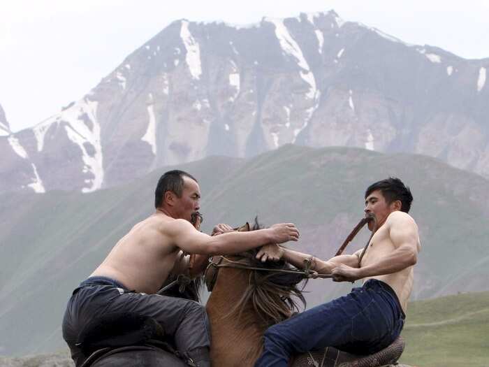 In the Osh region of Kyrgyzstan, men on horseback wrestle one another trying to dismount their opponent during the Kyrgyz horse games and festival.