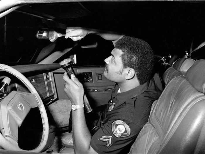 Agent Calvin Pratt dusts for fingerprints in a recovered stolen vehicle.