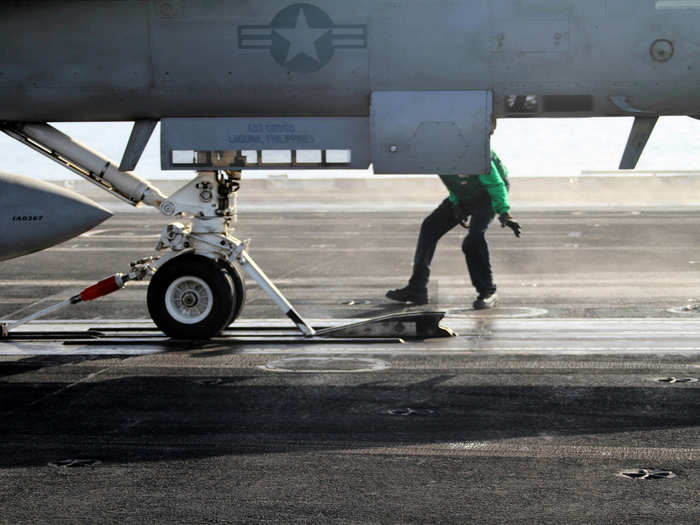 This "Hookup Man" is guiding the F/A-18 into the launch catapult, easing the plane