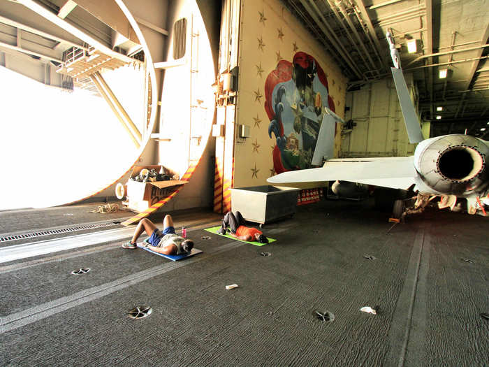 Because of its sheltered and open space, the hangar deck is one place sailors exercise to stay fit for their physical fitness tests.