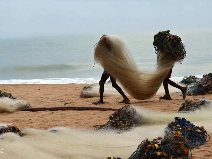 Two young anglers in Greater Accra, Ghana carry fishing nets to their boat.