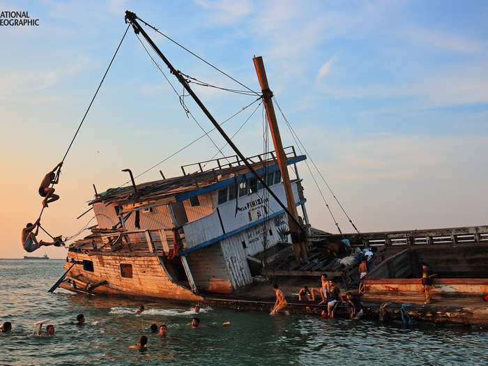 Children in The Port Paotere play near a centuries-old shipwrecked wooden boat, Pinisi, which once explored the boundaries of Makassar in South Sulawesi, Indonesia.