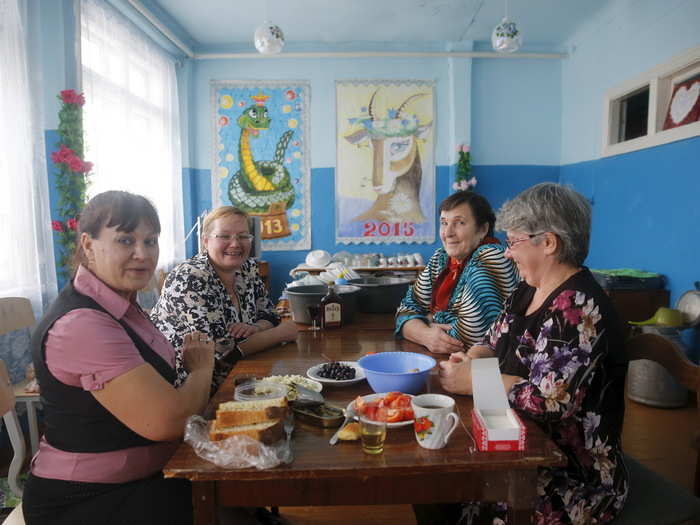 Inside, villagers Elena, Olga, Galina and Tatiana drink and eat in warmth.