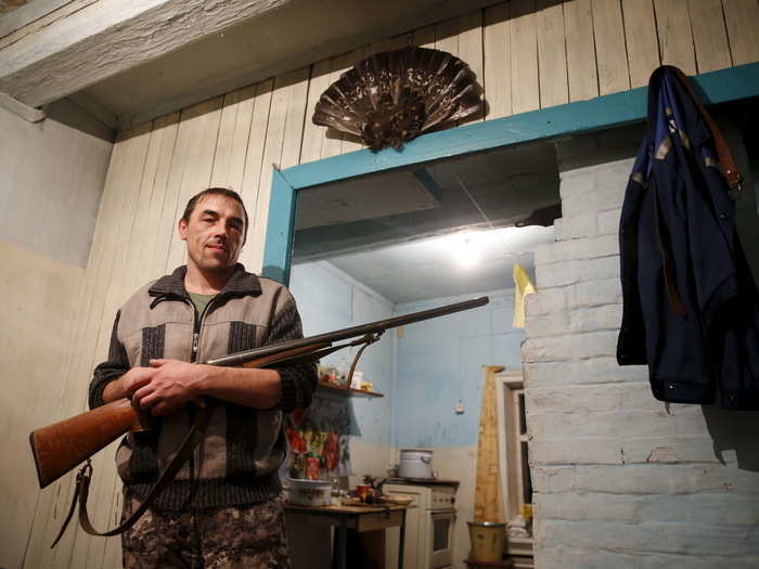 Here, villager Alexander poses with his gun in his small Kalach home. He is one of 12 residents left in this tiny outpost at the end of the rail line.