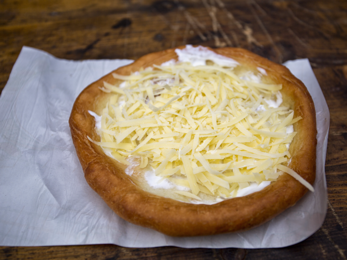 HUNGARY: Láng os consists of deep-fried flatbread that can be topped with a variety of ingredients, including sour cream, grated cheese, ham, sausages, vegetables, or garlic.