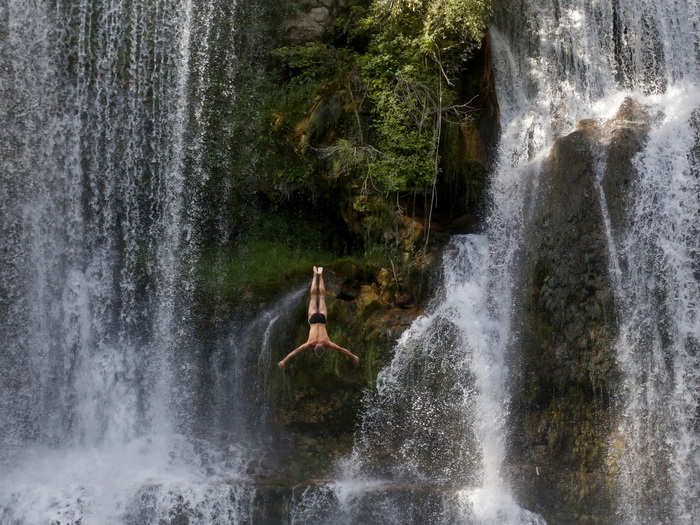 A participant in the first international waterfall jumping competition jumps down a flowing stream in the Bosnian city of Jajce.