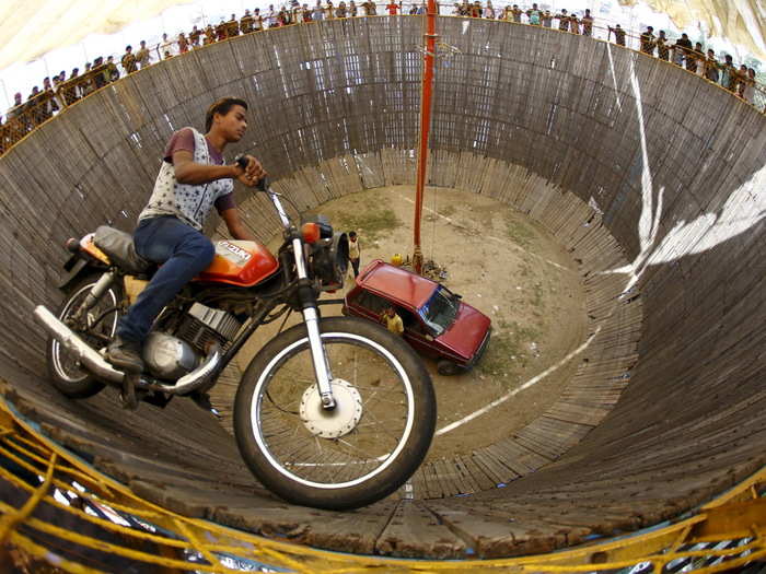 A stuntman rides a motorcycle inside an attraction nicknamed the "Well of Death" during a fair in Nepal.