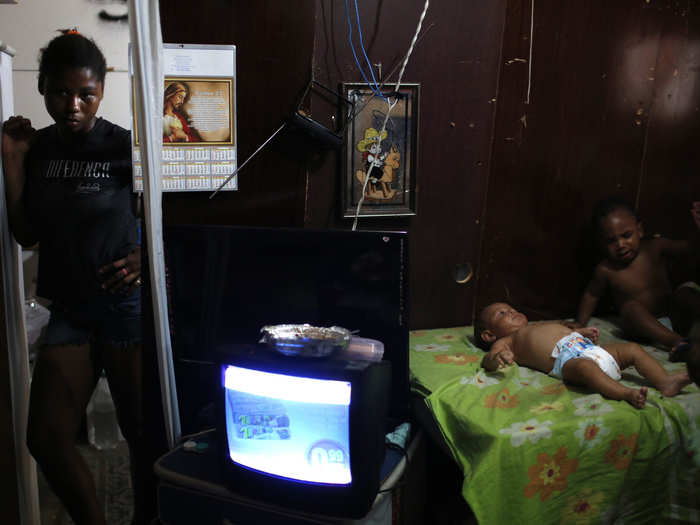 A babysitter stands at the entrance to a makeshift home within the Nova Tuffy slum of Rio de Janeiro.