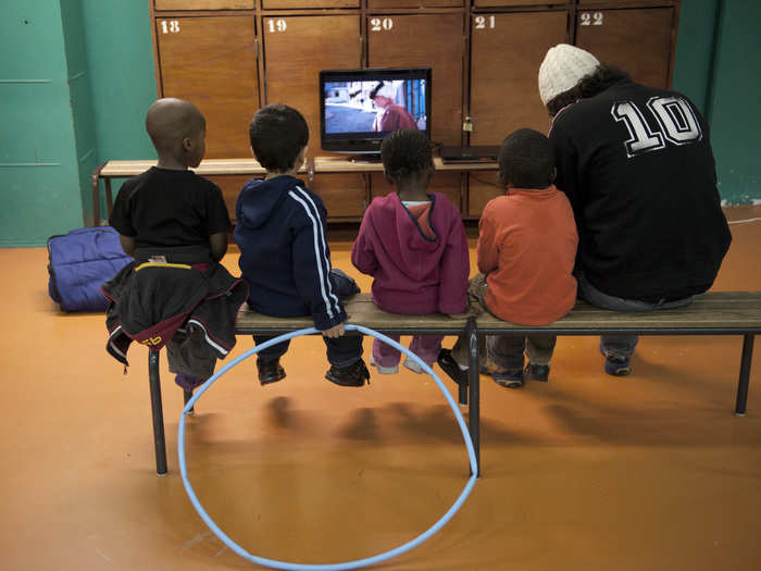 The Saint-Merri gym in Paris shows TV programming as children sit on the bench and watch.