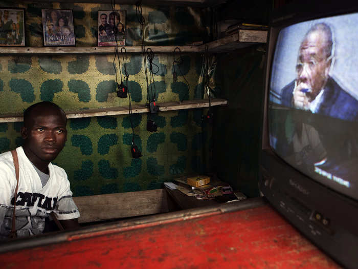 A street vendor watches a live broadcast as the (now former) Liberian president Charles Taylor is convicted of aiding and abetting war crimes in 2012.