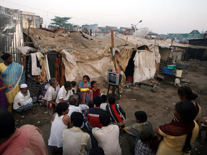 Outside of their homes in Mumbai, India, neighbors of Azharuddin Ismail gather to watch an Oscars ceremony. Ismail played the youngest version of the main character in the 2008 movie "Slumdog Millionaire," which takes place in the same slums.