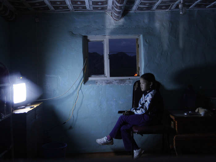 A young girl watches TV in a house at a tourist campsite in the Bulgan province of Mongolia.