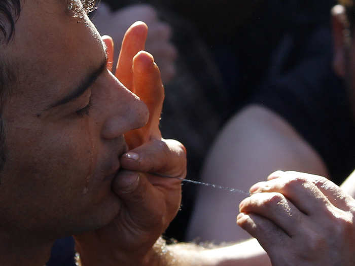 A migrant gets his mouth sewed up during a protest as he waits with others to cross the border from Greece to Gevgelija, Macedonia.