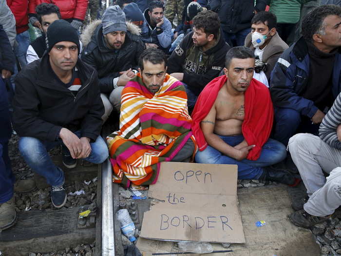 Stranded Iranian migrants sit on rail tracks at the border between Greece and Macedonia in front of Macedonian riot police near the Greek village of Idomeni.