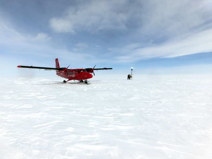 In this picture, a 19-seater Twin Otter passenger plane sits atop the ice sheets of Greenland while two people inspect a weather station.