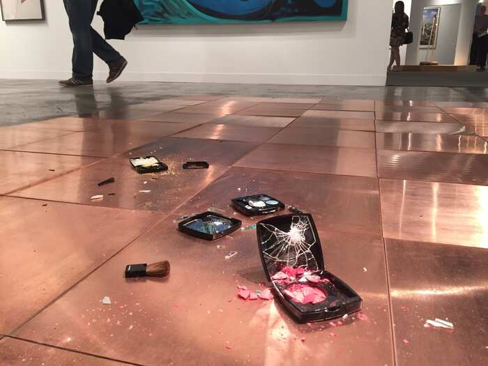 This piece by Lorna Simpson features broken makeup compacts on the floor.