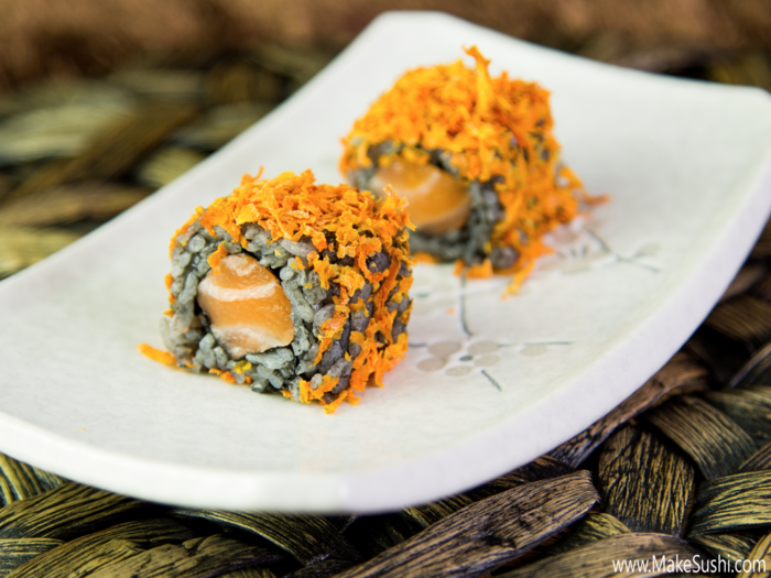 This Halloween inspired sushi roll features salmon, black rice (dyed with squid ink), and shavings of dehydrated carrot.