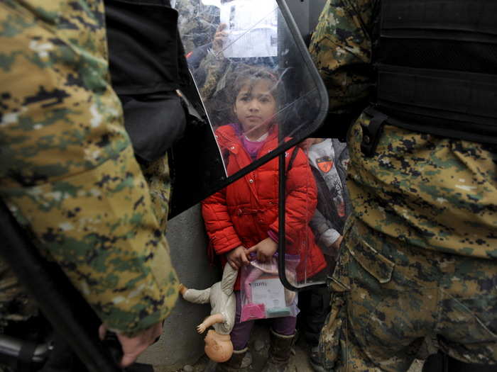 A girl holds her toys as Macedonian policemen block refugees at the Greek-Macedonian borders, near the village of Idomeni, Greece November 20, 2015.