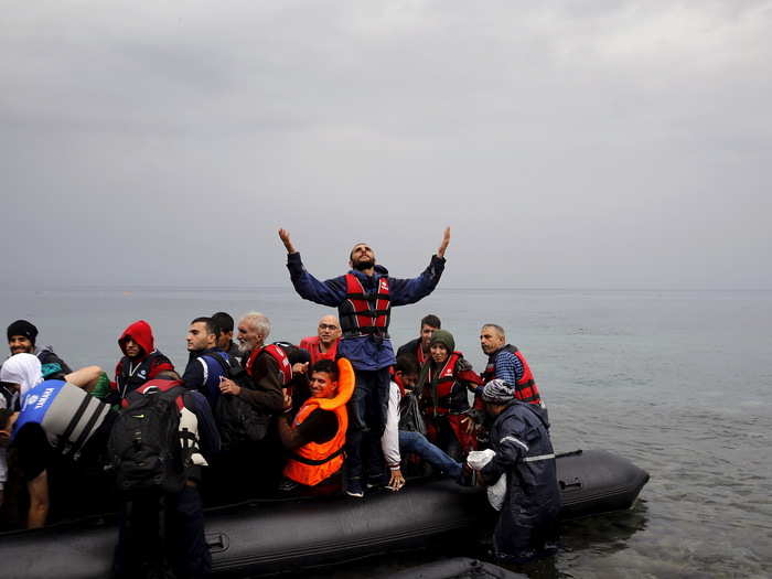 A Syrian refugee gives thanks as he arrives in an overcrowded dinghy on the Greek island of Lesbos after crossing part of the Aegean Sea from Turkey September 23, 2015.