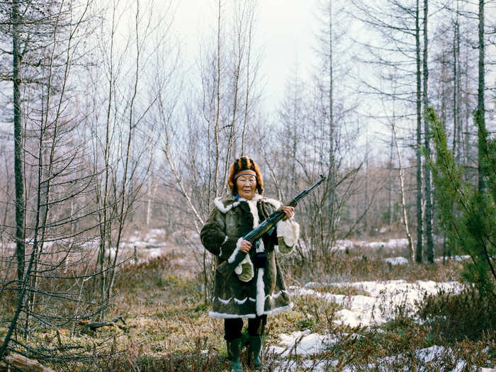 Maria Ivanova, seen here in traditional Evenk dress, is holding a rifle used for practice shooting after a family picnic in the forest in Zhigansk. The Evenk people are an indigenous ethnic group from Northern Asia. The Russian Evenks live mostly in the Siberian taiga, where their population is around 35,000.