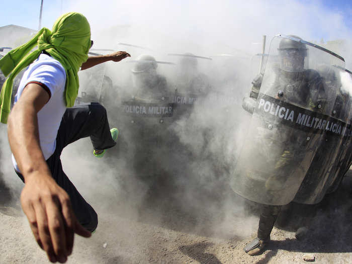 An activist kicks the shields of the military police officers during a demonstration in the military zone of the 27th infantry battalion in Iguala, Guerrero, January 12, 2015. Activists and relatives of 43 abducted trainee teachers from Ayotzinapa