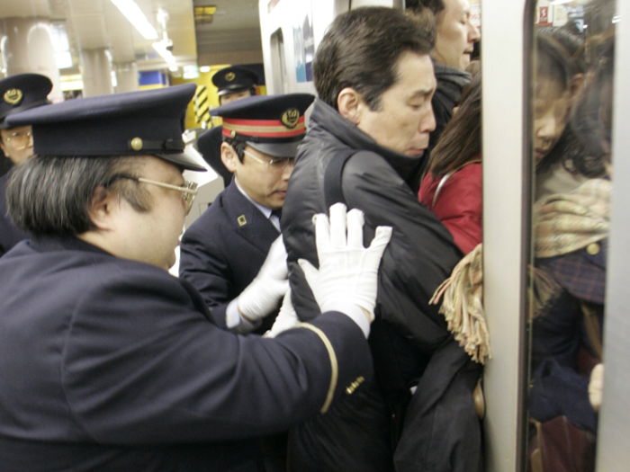 Ikebukuro station is part of the East Japan Railway Company, the largest rail operator in the world. Attendants patrolling the station must physically push riders onto the trains to accommodate the traffic.