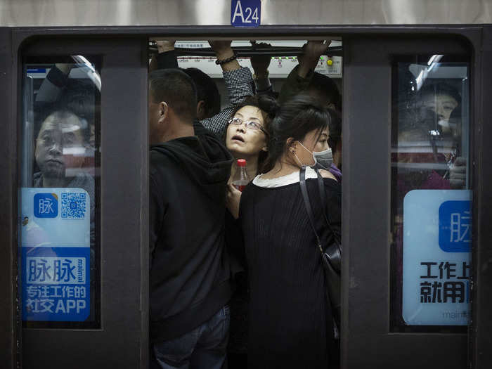 Riders in Beijing crowd into a subway car at rush hour. The woman