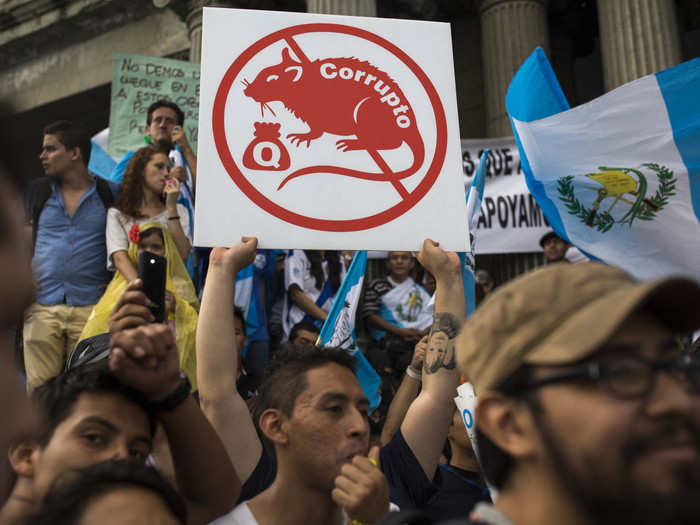 GUATEMALA: A protester holds up a sign showing a rat covered with the Spanish word "Corrupt" outside the National Palace during a national strike demanding the resignation of Guatemalan President Otto Perez Molina in Guatemala City, August 27, 2015.