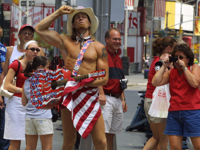 Robert Burck, better known as "The Naked Cowboy," started busking in Times Square in 1998. By this 2002 photo, he had become a tourist fixture.