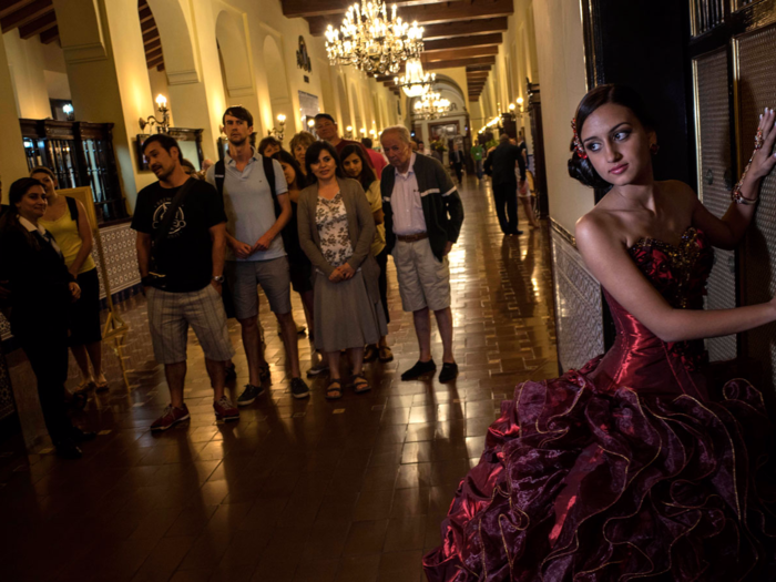 Gladys Barroso Quintana has her photo taken while tourists watch. While some of the older traditions — like the waltz — remain, the focus of quinceañeras in Cuba is the photographs.