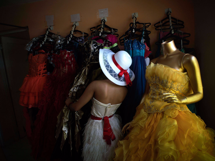 Dresses often include ruffles, shimmering detail, and a variety of colors that range from bold red hues to rich blues. In this photo, Daniel Santos Torres, who left Cuba when she was three, picks out a dress. She returned in December just for her quinceañera party.