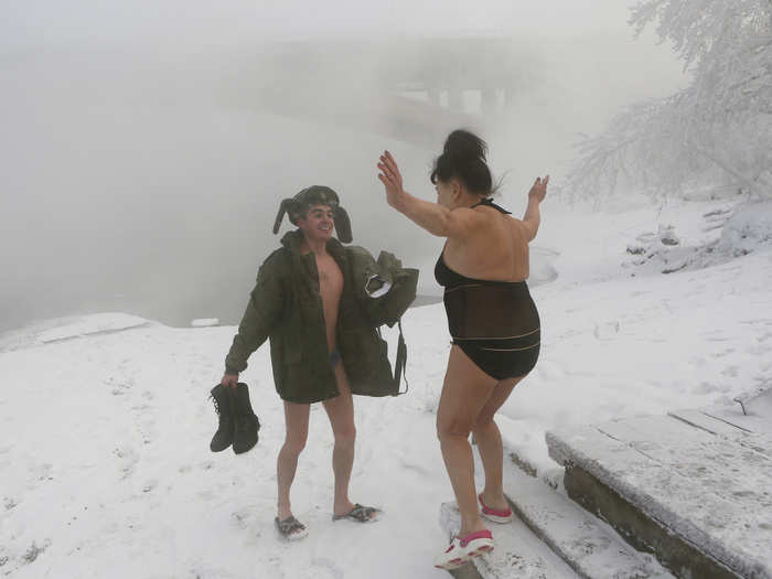 Members greet each other as they get ready for a swim on the banks of the Yenisei River.