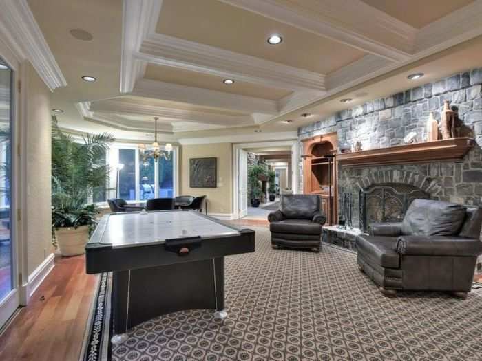 The massive stone fireplace in the game room faces an air hockey table.