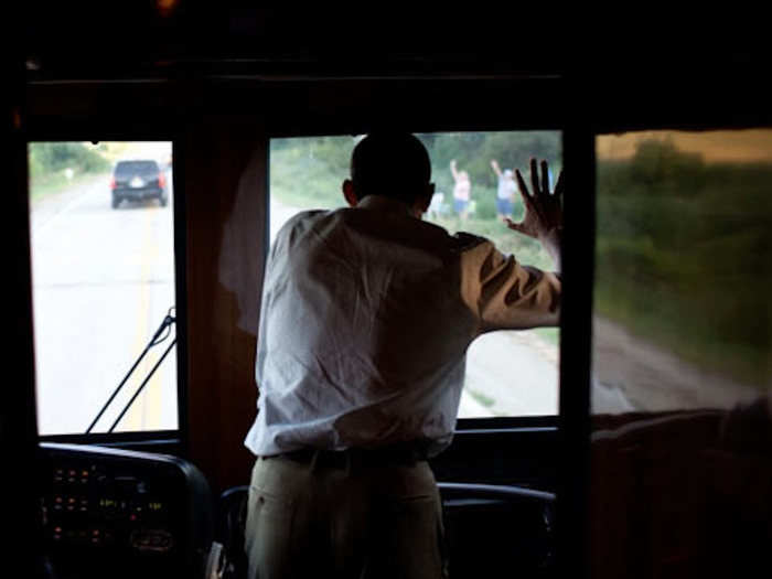 Since all the windows except the ones at the front of the bus are heavily tinted, President Obama has to stand next to the driver in order to wave at crowds.