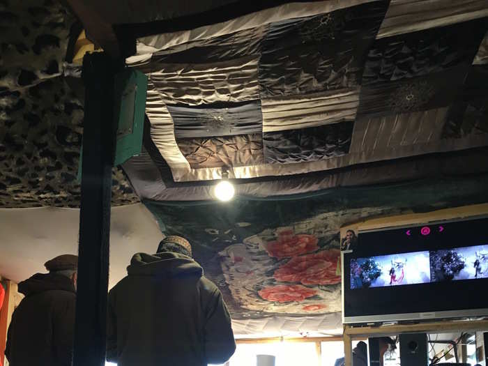 This is the interior of one of the cafes in the camp. It is decorated with different blankets and cloths that are hung on the ceiling, and also has television.